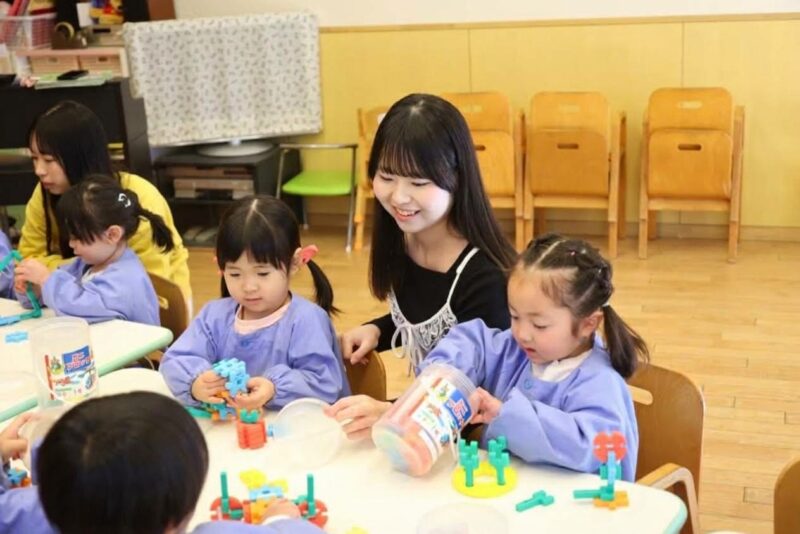 ブロックで作った作品を見せるこどもたちと、笑顔の辻村さん